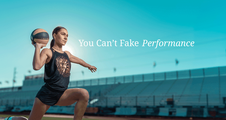 A focused woman in athletic wear kneels on a track, holding a basketball with one arm raised. The background shows empty stadium seats and the text “You Can’t Fake Performance.”.