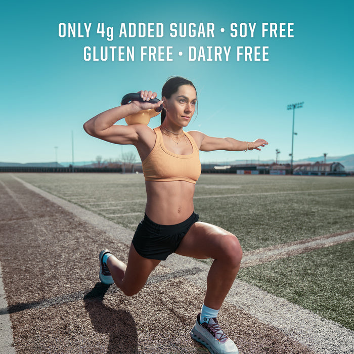 Woman in athletic wear lunging with a resistance band on an outdoor sports field under clear sky
