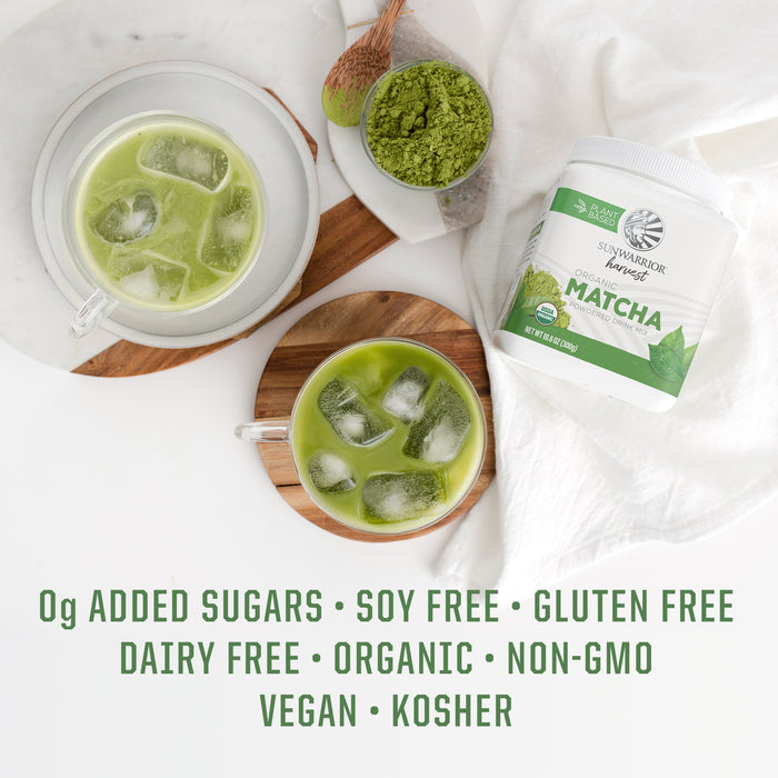 Two iced matcha drinks, a scoop of green matcha powder, and a container of organic matcha powder on white cloth.