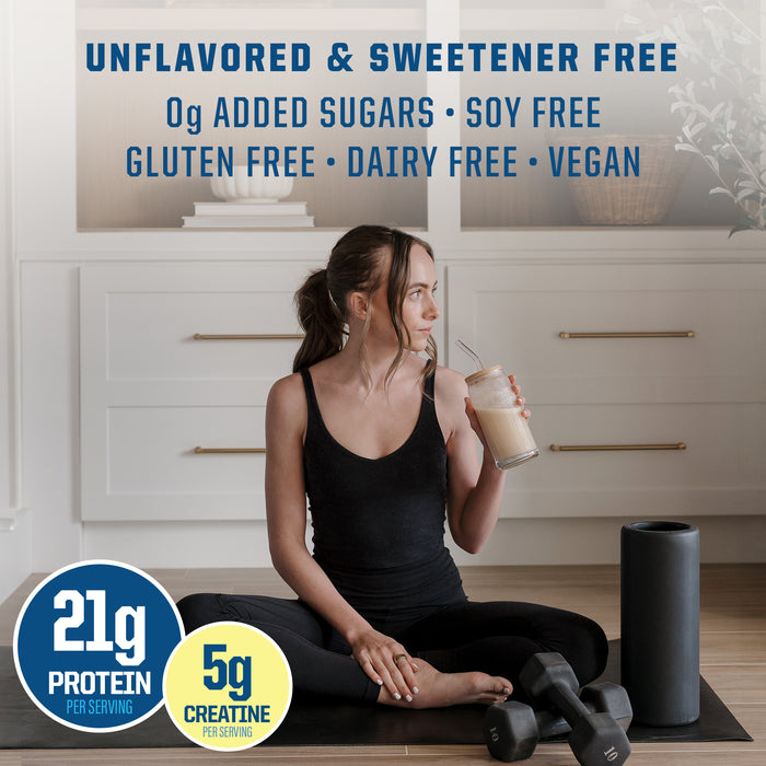 Woman in black workout clothes sitting with protein shake, dumbbells, and foam roller in bright kitchen area