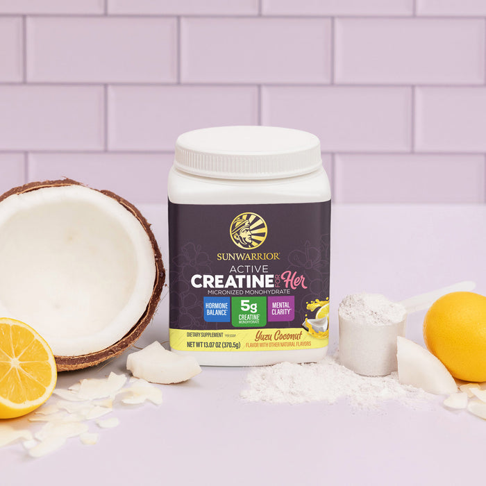 Sunwarrior Active Creatine for Her container with yuzu, coconut, powder, and sliced fruit on lavender tiles