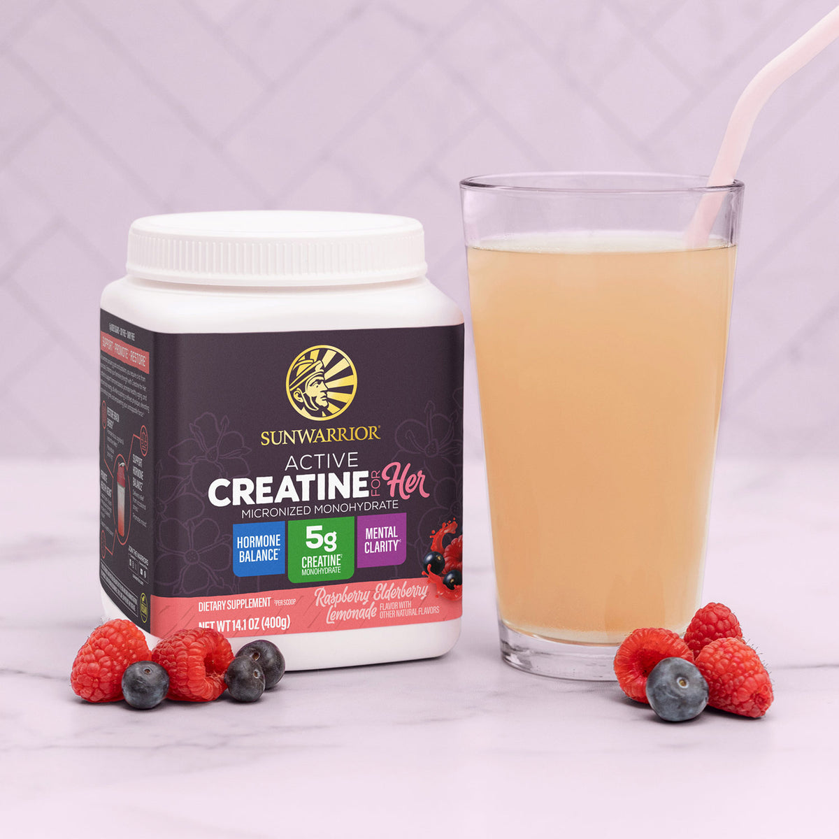 Container of Sunwarrior Active Creatine for Her with berries and a glass of light pink smoothie