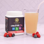Container of Sunwarrior Active Creatine for Her with berries and a glass of light pink smoothie