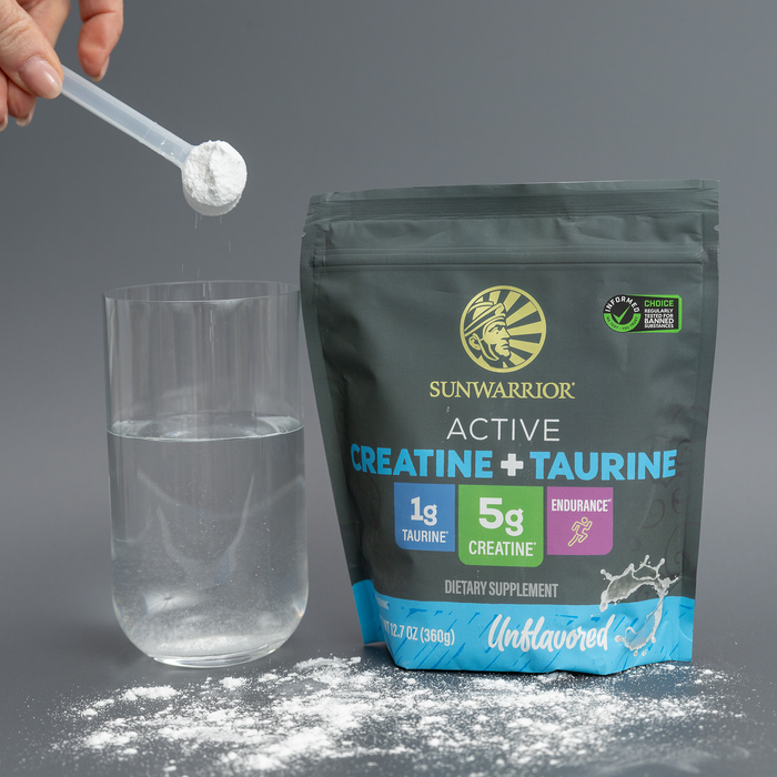 Sunwarrior Active Creatine and Taurine dietary supplement bag with a scoop pouring powder into water