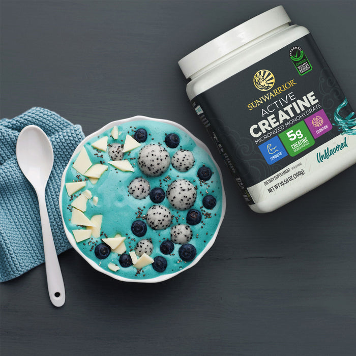 Sunwarrior Active Creatine container beside a blue smoothie bowl with fruit and white chocolate pieces