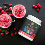 Container of Sunwarrior creatine powder beside two raspberry smoothies with ice on black surface