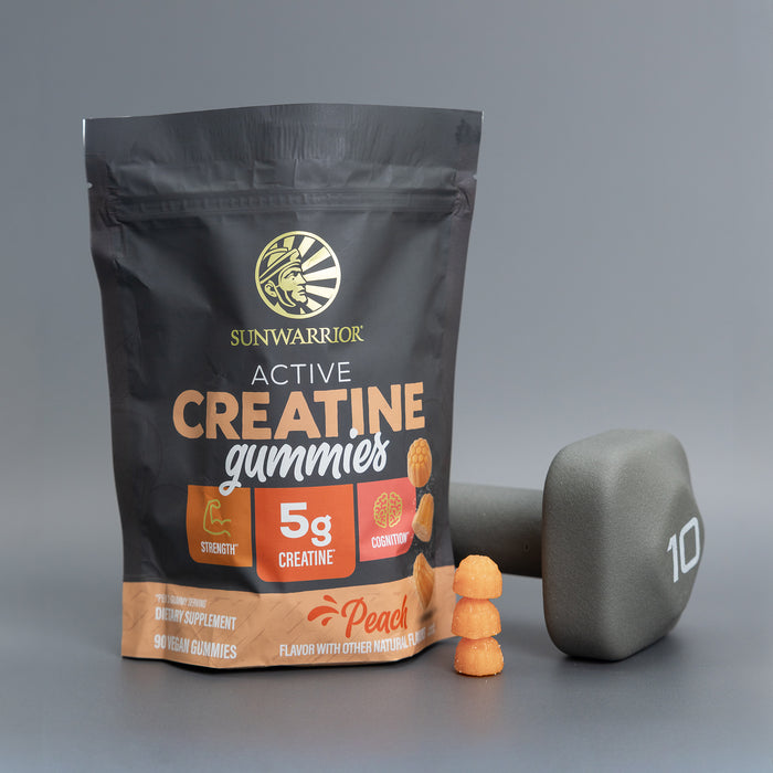 Black pouch of peach-flavored creatine gummies with stack of gummies and gray 10-pound dumbbell nearby