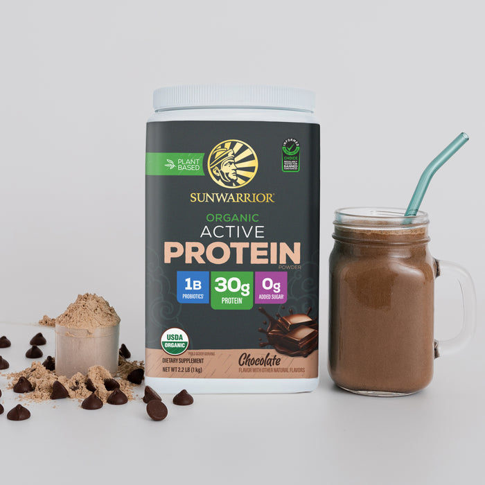 Container of Sunwarrior organic chocolate plant-based protein powder with a chocolate smoothie in a glass jar