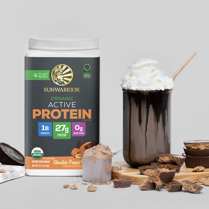 Container of plant-based organic chocolate peanut protein powder with a chocolate smoothie topped with whipped cream