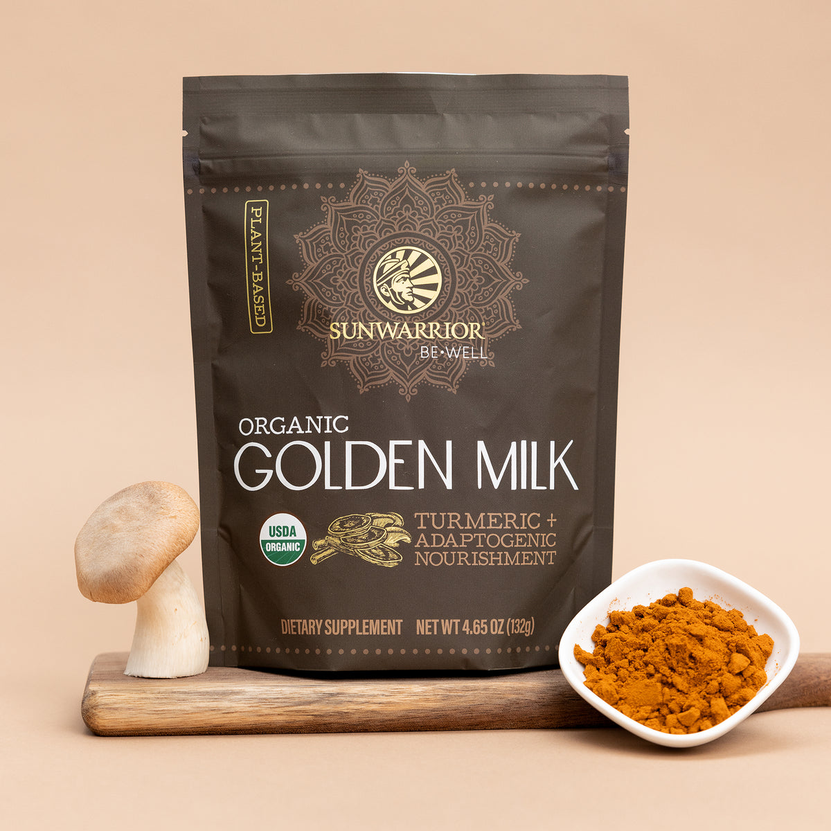 Package of organic golden milk powder with turmeric and adaptogenic nourishment beside mushroom and bowl of turmeric powder