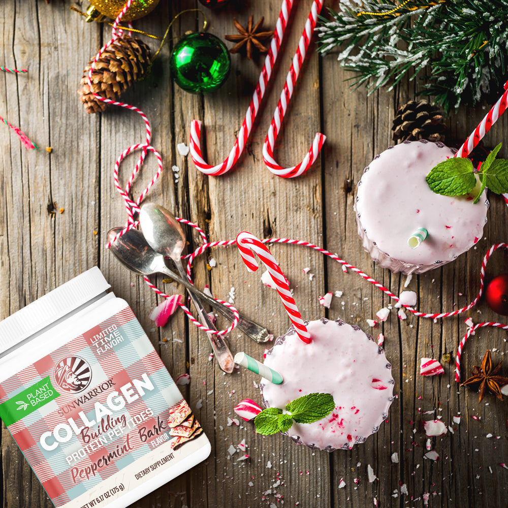 Two peppermint-flavored smoothies with candy canes, near protein powder and holiday decorations on wood