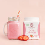 Jar of pink strawberry smoothie with a plant-based cleanser tub and sliced strawberries on a pale background