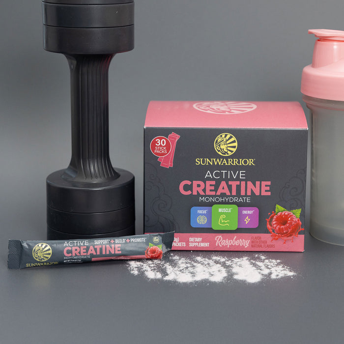 Sunwarrior Active Creatine raspberry flavor with dumbbell and shaker bottle on gray background.