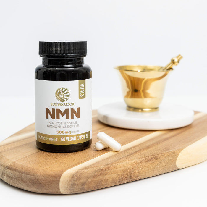 Sunwarrior NMN supplement bottle on a wooden cutting board with a white background