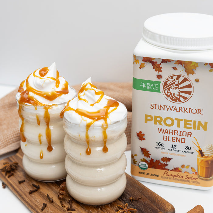 Two creamy pumpkin spice smoothies topped with caramel drizzle beside a Sunwarrior plant-based protein container