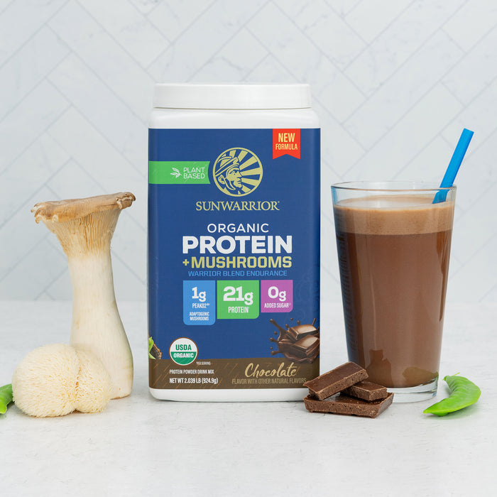 Container of plant-based chocolate protein powder with mushrooms next to a smoothie and fresh mushrooms
