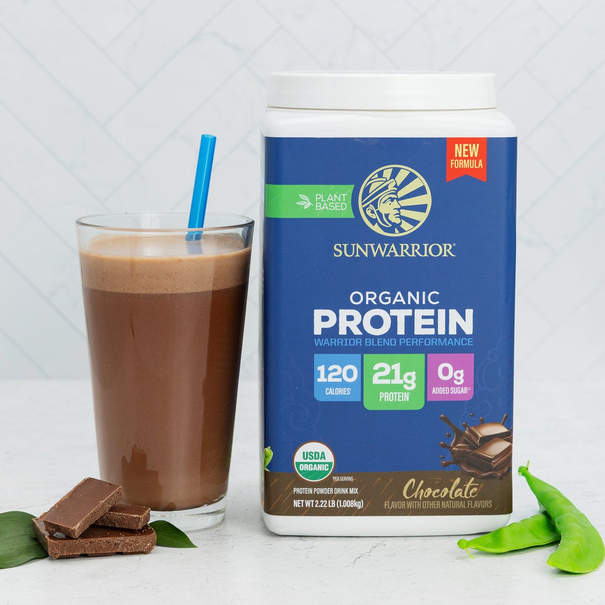 Container of Sunwarrior plant-based organic chocolate protein with a glass of chocolate shake and chocolate pieces nearby