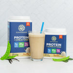 Two containers of vanilla plant-based protein powder and creatine by Sunwarrior with a vanilla smoothie in a glass and green leaves nearby