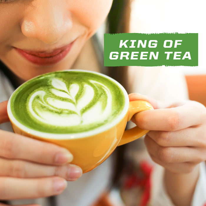 Close-up of person holding a yellow cup with green tea latte art and text 