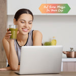 Woman holding a green smoothie near a laptop with a colorful sign saying Put Some Magic In Your Cup
