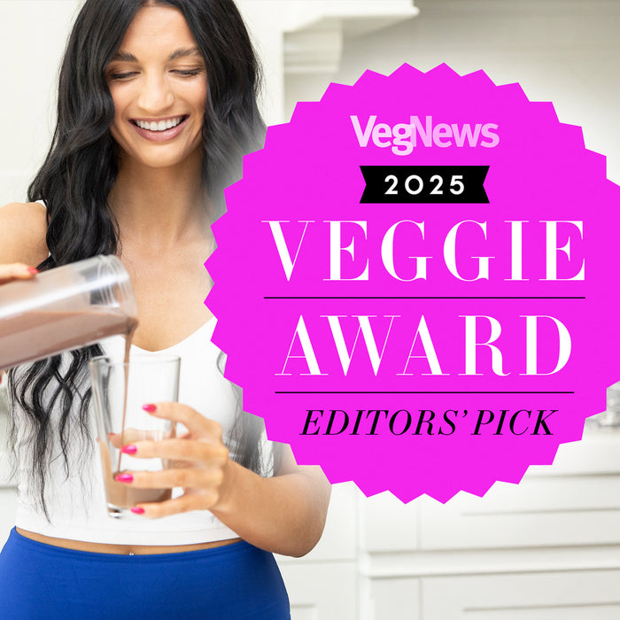 Woman pouring chocolate smoothie into glass next to bright pink VegNews 2025 Veggie Award badge
